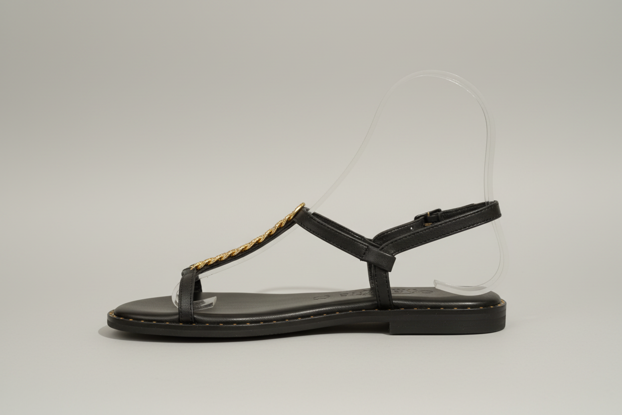 Sandale plate en cuir noir véritable, ornée d'une délicate feuille dorée sur le cou de pied. Design épuré et intemporel pour un confort quotidien