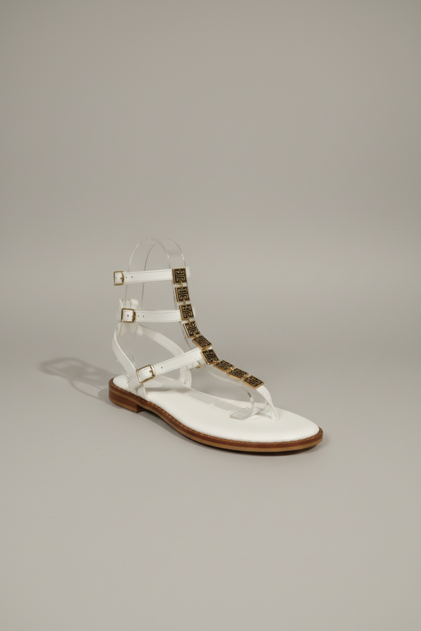 Sandale plate cuir blanche feuille dorée sur cou de pied, petit talon tout cuir, première rembourée pour un confort optimal. Design épuré et élégant, parfait pour l'été.