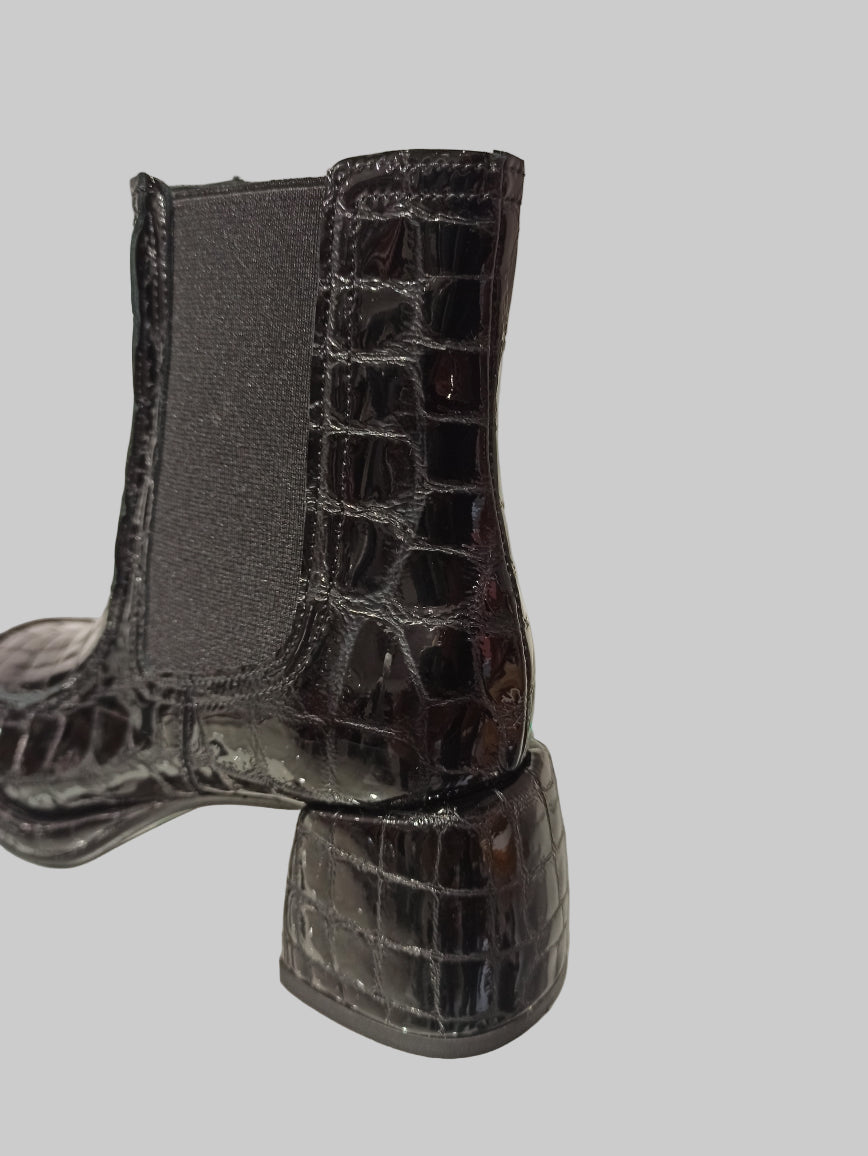 Alliant élégance et caractère, ces Chelsea boots en cuir vernis noir embossé offrent un style unique et contemporain. Leur talon carré de 4 cm assure une démarche confortable et raffinée, tandis que la semelle en cuir garantit durabilité et qualité. Idéales pour sublimer vos looks avec une touche sophistiquée, ces boots sont un incontournable pour celles qui recherchent à la fois style et confort.