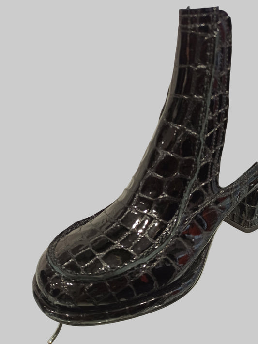 Alliant élégance et caractère, ces Chelsea boots en cuir vernis noir embossé offrent un style unique et contemporain. Leur talon carré de 4 cm assure une démarche confortable et raffinée, tandis que la semelle en cuir garantit durabilité et qualité. Idéales pour sublimer vos looks avec une touche sophistiquée, ces boots sont un incontournable pour celles qui recherchent à la fois style et confort.