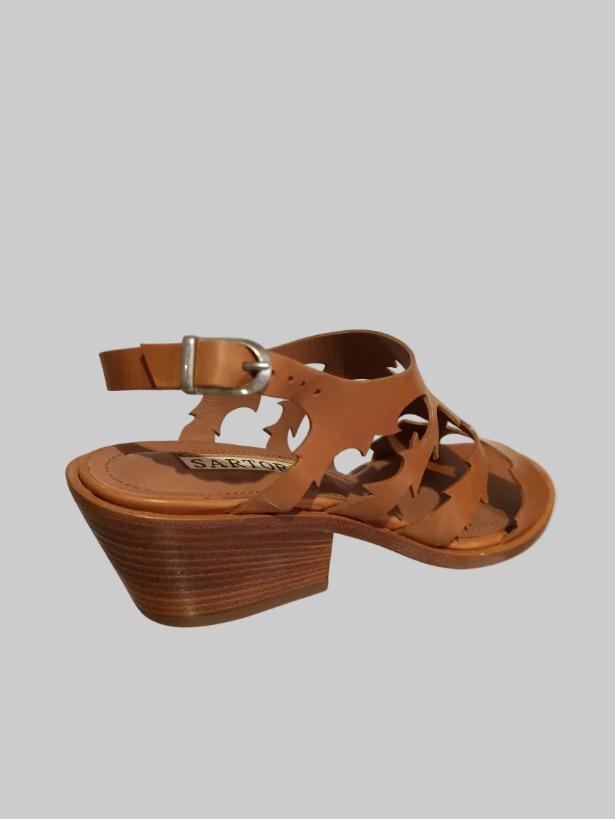 Découvrez les sandales Sartore, une fusion audacieuse entre élégance western et raffinement contemporain. Dotées d'un talon de 5 cm qui allonge la silhouette sans compromettre le confort, ces sandales allient style santiag intemporel et détails sophistiqués. Le cuir camel premium, travaillé par des découpes laser précises, crée un motif géométrique captivant qui capture la lumière à chaque pas. La semelle cousue main garantit une durabilité exceptionnelle et un maintien optimal, tandis que la construction a