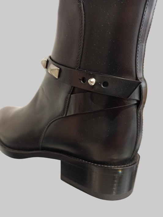 Bottes Sartore en cuir lisse noir, sublimées par une bride ornée de clous argentés. Un design intemporel qui allie élégance classique et détails rock chic. Le cuir premium garantit confort et durabilité, tandis que les clous apportent une touche de caractère affirmé. Parfaites pour structurer vos tenues, du jour au soir. Une paire d'exception qui devient rapidement indispensable.