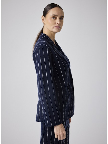 Cette veste blazer Owen marine allie élégance et confort grâce à sa coupe tailleur soulignée par une surpiqûre écrue raffinée. Conçue avec un mélange haut de gamme de 90 % laine et 10 % cachemire, elle vous assure chaleur et douceur tout en renforçant votre allure élégante. Idéale pour sublimer toutes vos tenues, cette pièce essentielle offre une silhouette structurée avec ses deux boutons et revers classiques. Adoptez un style chic et contemporain avec cette veste polyvalente qui vous accompagnera au quoti