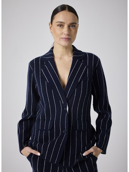 Cette veste blazer Owen marine allie élégance et confort grâce à sa coupe tailleur soulignée par une surpiqûre écrue raffinée. Conçue avec un mélange haut de gamme de 90 % laine et 10 % cachemire, elle vous assure chaleur et douceur tout en renforçant votre allure élégante. Idéale pour sublimer toutes vos tenues, cette pièce essentielle offre une silhouette structurée avec ses deux boutons et revers classiques. Adoptez un style chic et contemporain avec cette veste polyvalente qui vous accompagnera au quoti