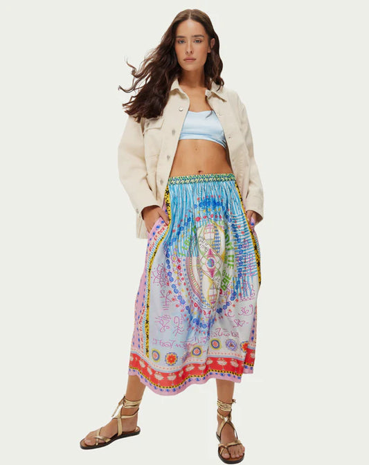 Jupe midi Vanessa aux sept symboles des chakras alignés verticalement dans des couleurs arc-en-ciel éclatantes. Des rayures turquoise en haut se fondent progressivement dans des teintes rose doux et lilas, ornées de mystérieux scripts runiques et de géométrie sacrée. La taille élastique froncée crée du volume et du mouvement fluide, tandis que des bordures mandala colorées en corail, orange, jaune et violet encadrent l'ourlet avec des détails pointillés décoratifs. Les motifs spiralés et symboles spirituels