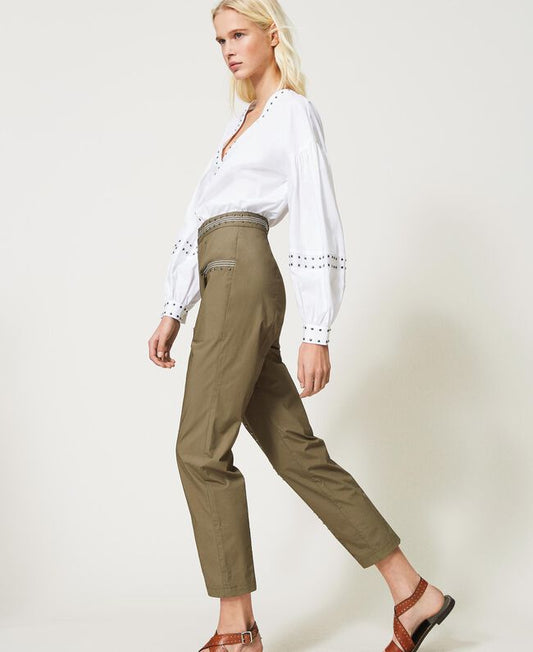 femme portant un pantalon taille haute fluide en popeline de coton kaki avec blouse blanche à broderies et sandales marron
